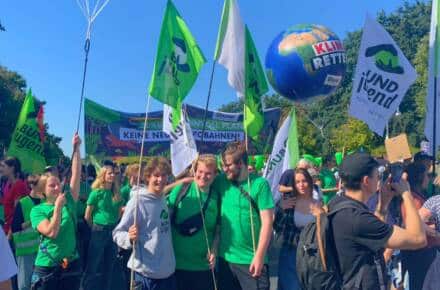 Menschen bei Klimaprotest mit Schildern und Fahnen.