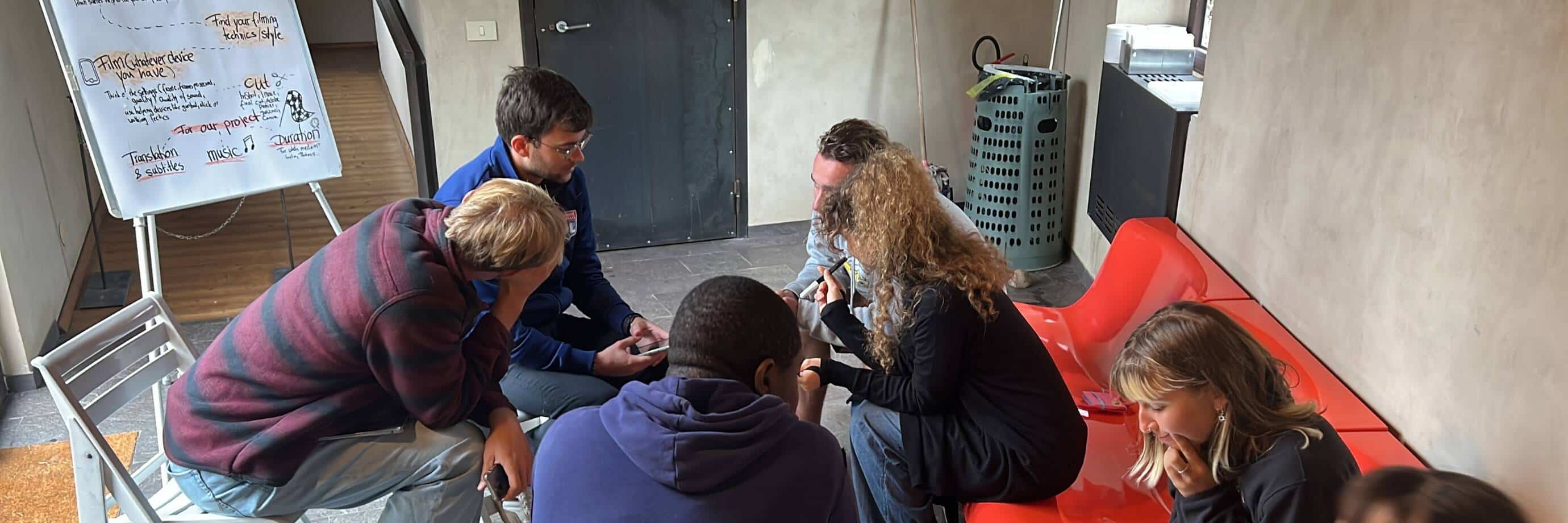 Gruppe bespricht Projektideen auf roten Sofas.