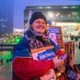 Lächelnde Person mit Schild bei Abendveranstaltung