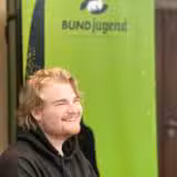 Junger Mann vor einer BUNDjugend Fahne