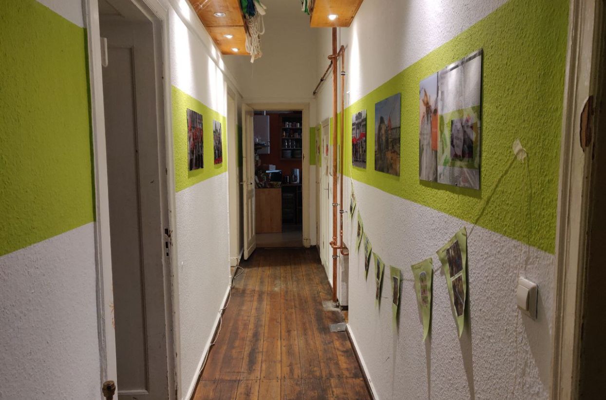 Langer Flur mit grünen Streifen und Bildern an den Wänden.