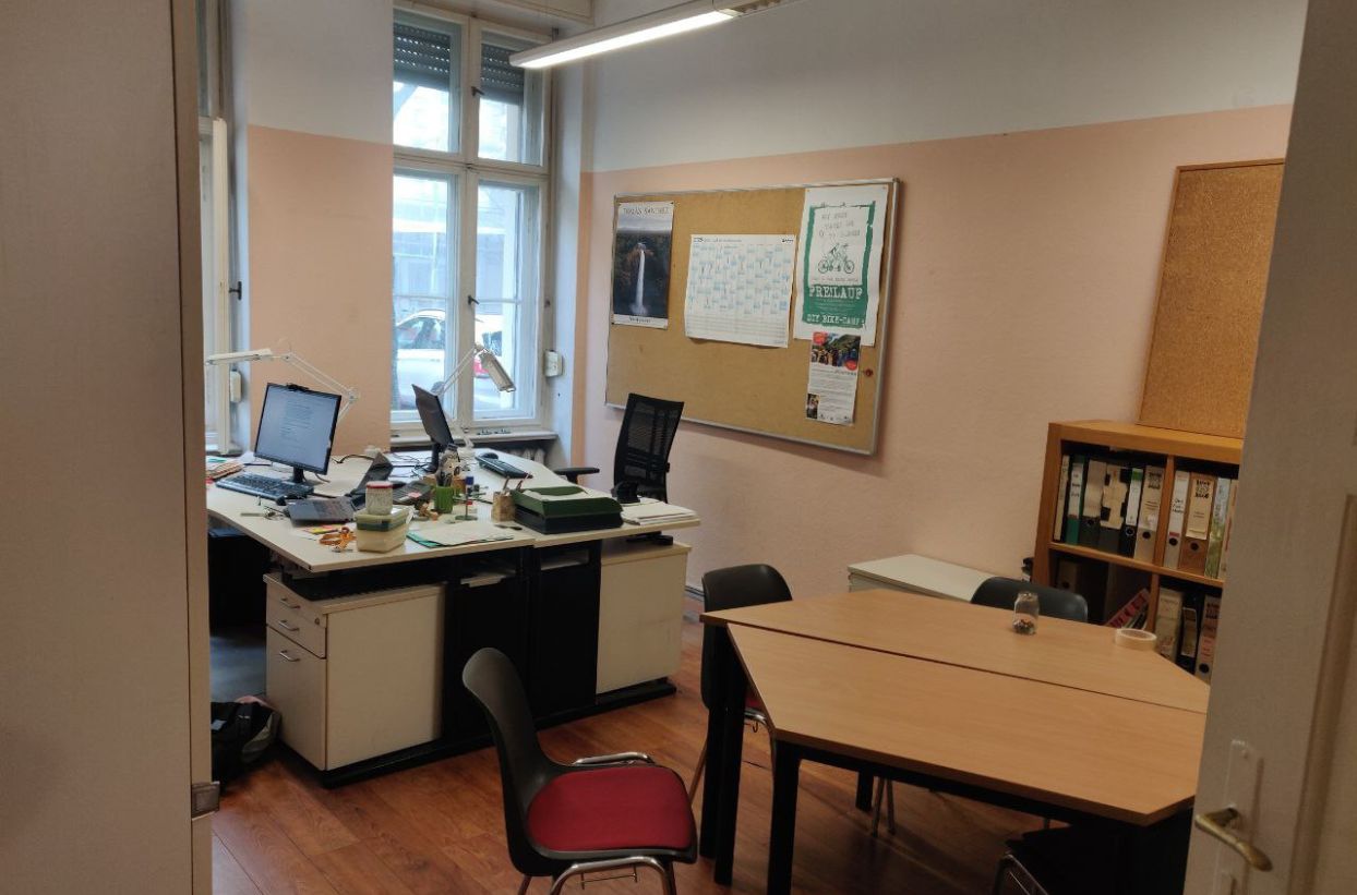 Büro mit Schreibtisch, Stühlen und Fenster.