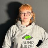Person mit BUNDjugend-Pullover vor dunklem Hintergrund