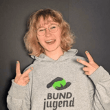 L&auml;chelnde junge Frau zeigt Peace-Zeichen