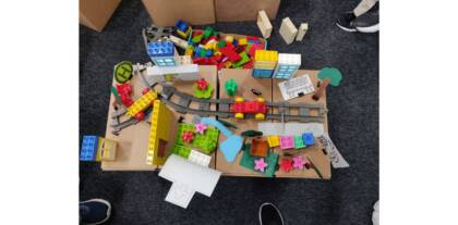 Selbstgebauter Kiez aus Lego und papier mit Schienen und Parks von oben.