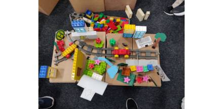 Selbstgebauter Kiez aus Lego und papier mit Schienen und Parks von oben.