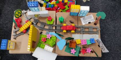 Selbstgebauter Kiez aus Lego und Papier mit Schienen und Parks von oben.