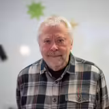 &Auml;lterer Mann in kariertem Hemd l&auml;chelt leicht.