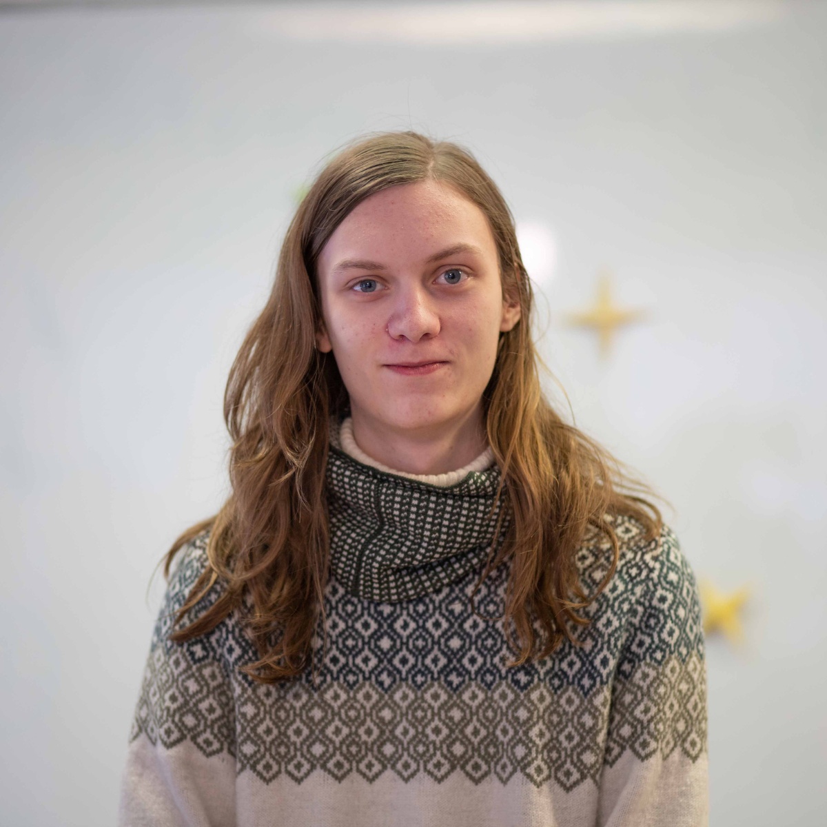 Person mit langen Haaren, freundlichem L&auml;cheln und buntem Pullover
