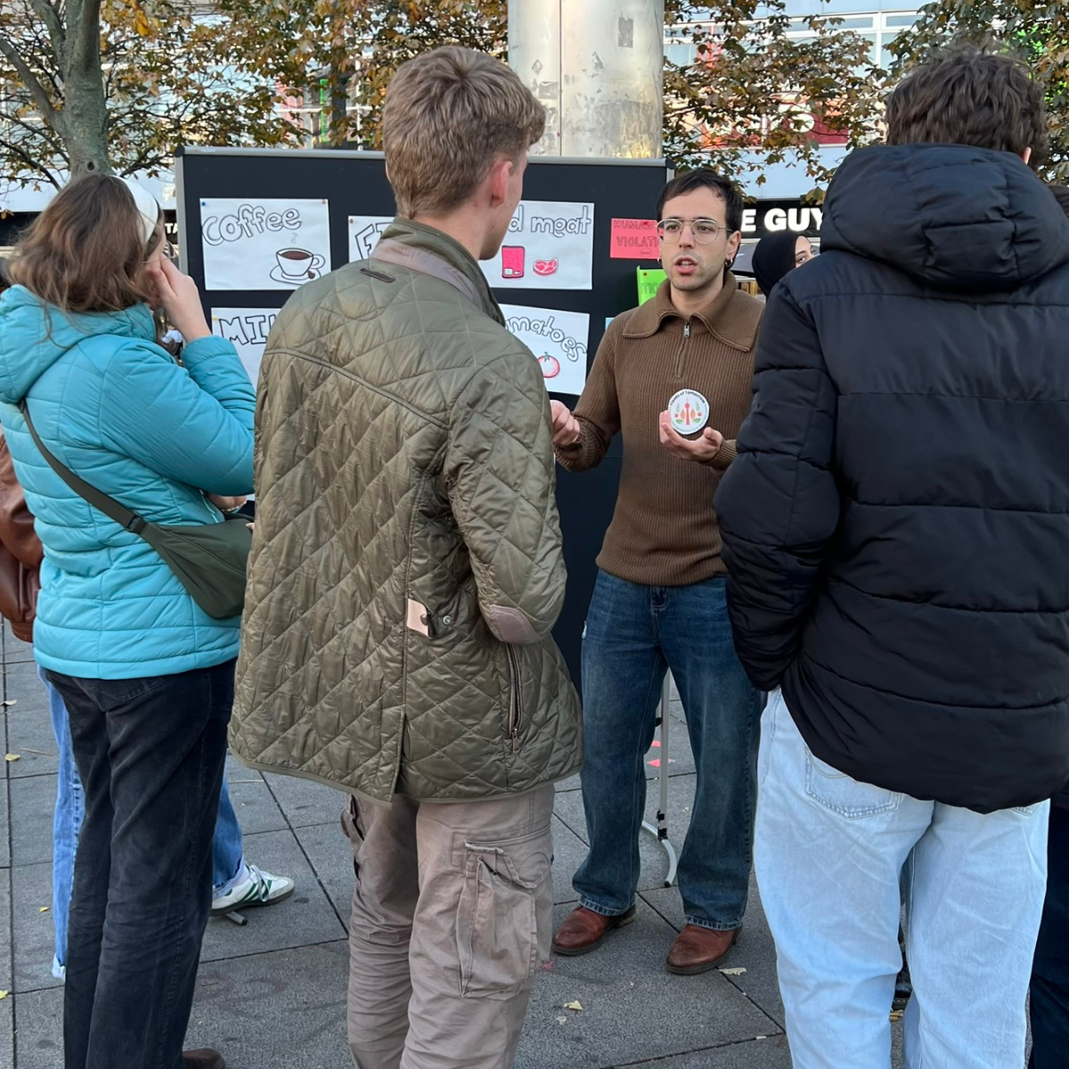 Mann erklärt einer Gruppe etwas am Infostand im Freien