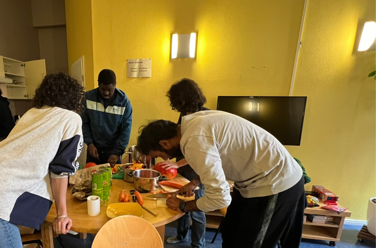 Gruppe kocht gemeinsam und schneidet Gemüse in Küche