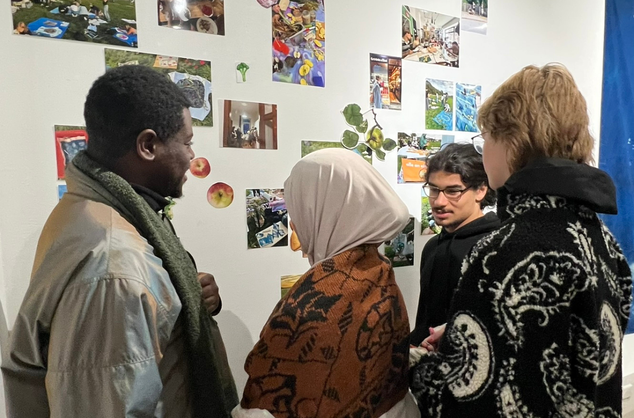 Vier Personen betrachten Fotocollage an einer Wand