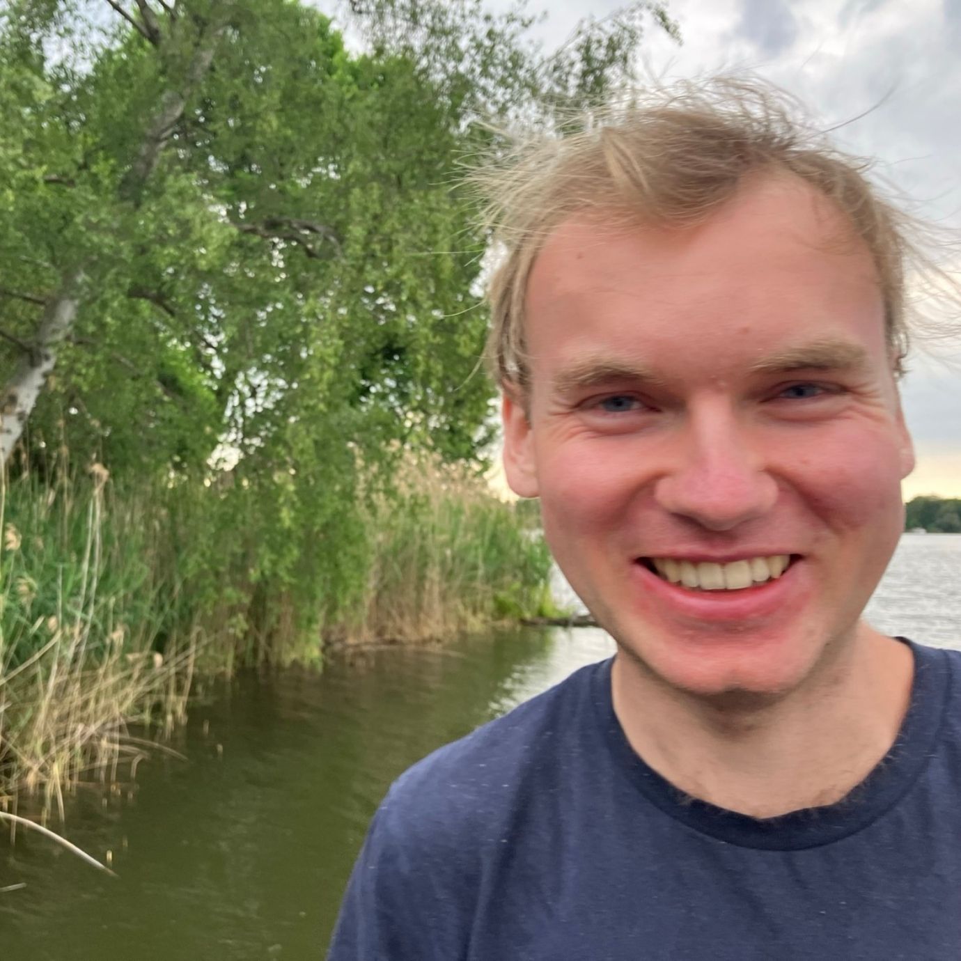 Lächelnder Mann am See mit Bäumen