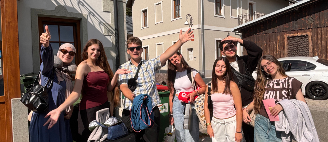 Gruppe junger Menschen steht mit Gepäck vor dem Hostel